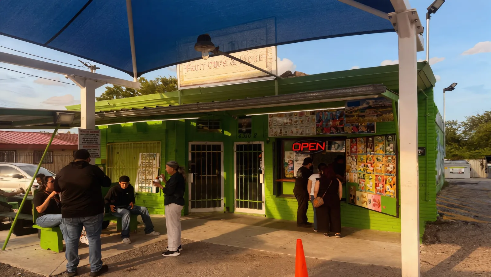 Customers outside the Las Nieves Fruit Cups & More stand on a golden San Antonio evening
