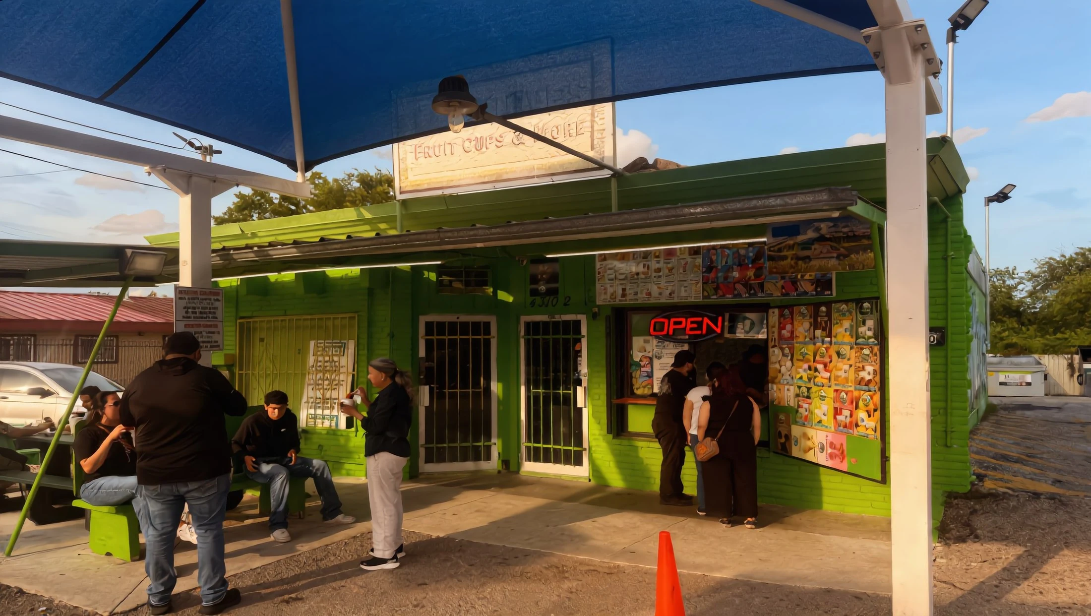 Customers outside the Las Nieves Fruit Cups & More stand on a golden San Antonio evening